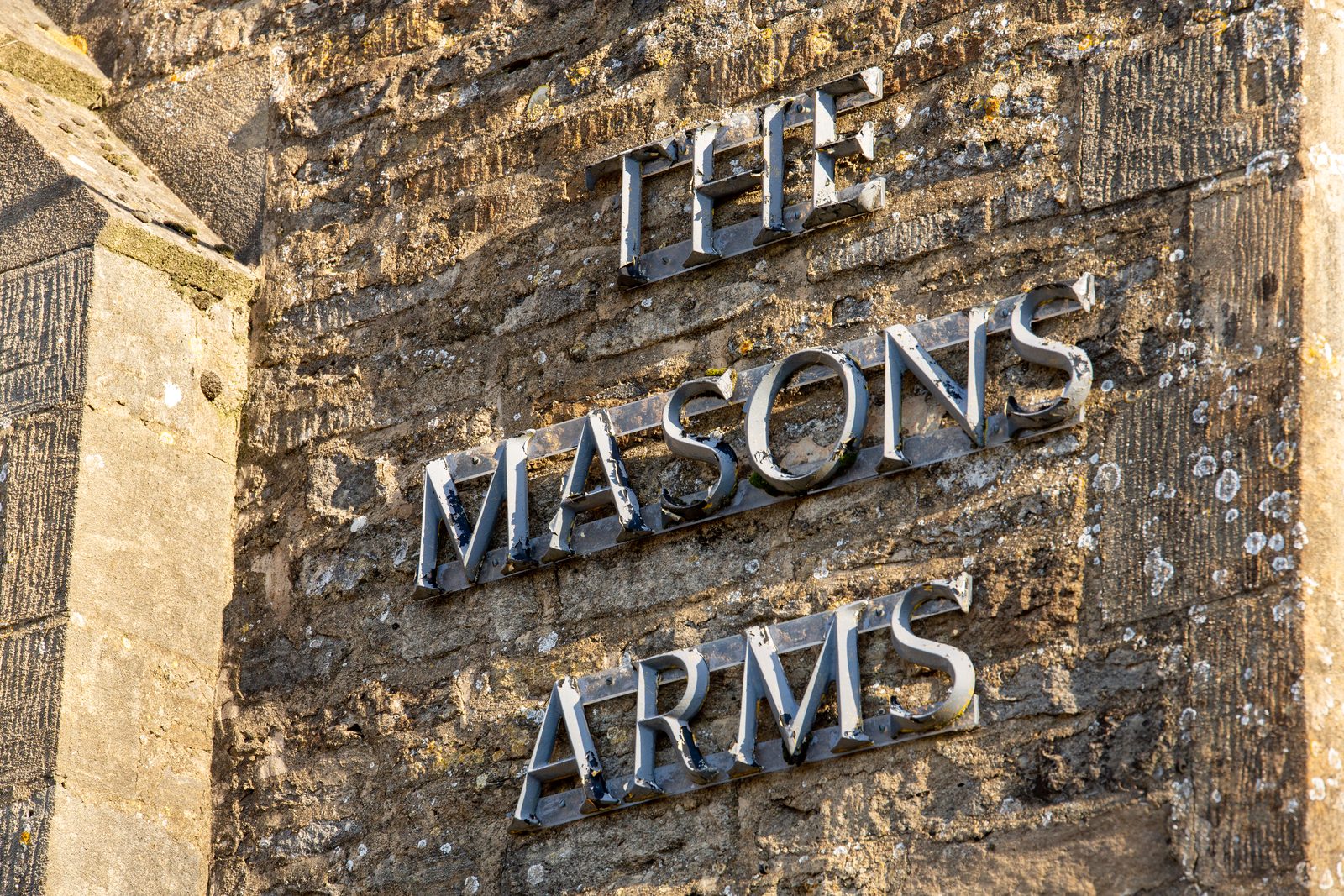 The Masons Arms lettering on the Cotswold stone wall